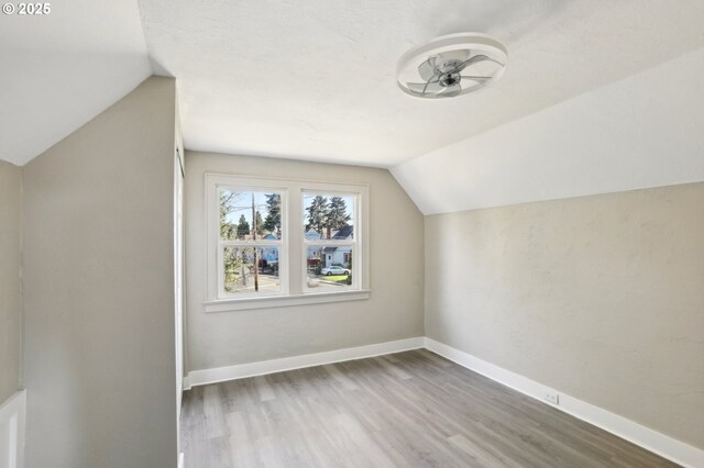 bonus room with baseboards, vaulted ceiling, and wood finished floors