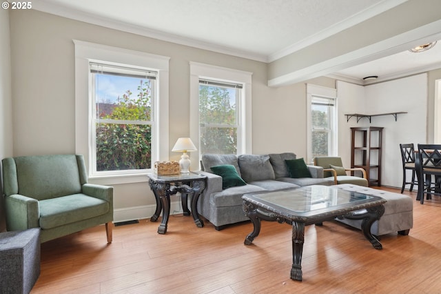 living area with visible vents, baseboards, light wood-style floors, and ornamental molding