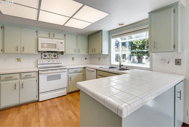 7430 SW Greens View Ct, Wilsonville, OR 97070 - kitchen featuring dishwasher, a sink, a peninsula, light wood finished floors, and tile counters