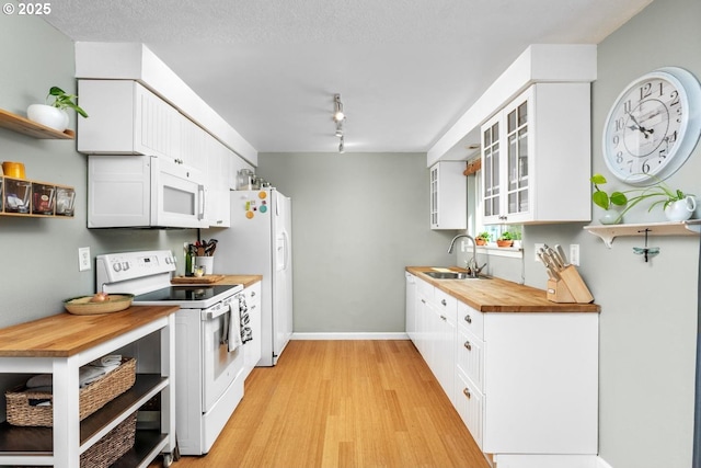kitchen featuring white appliances, a sink, light wood-style flooring, and white cabinetry