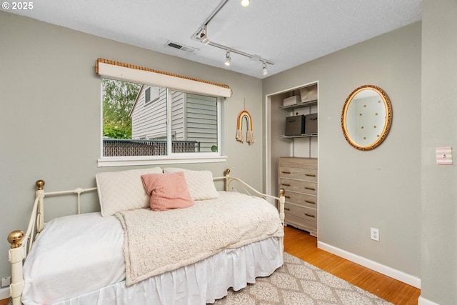 bedroom with wood finished floors, baseboards, and a closet
