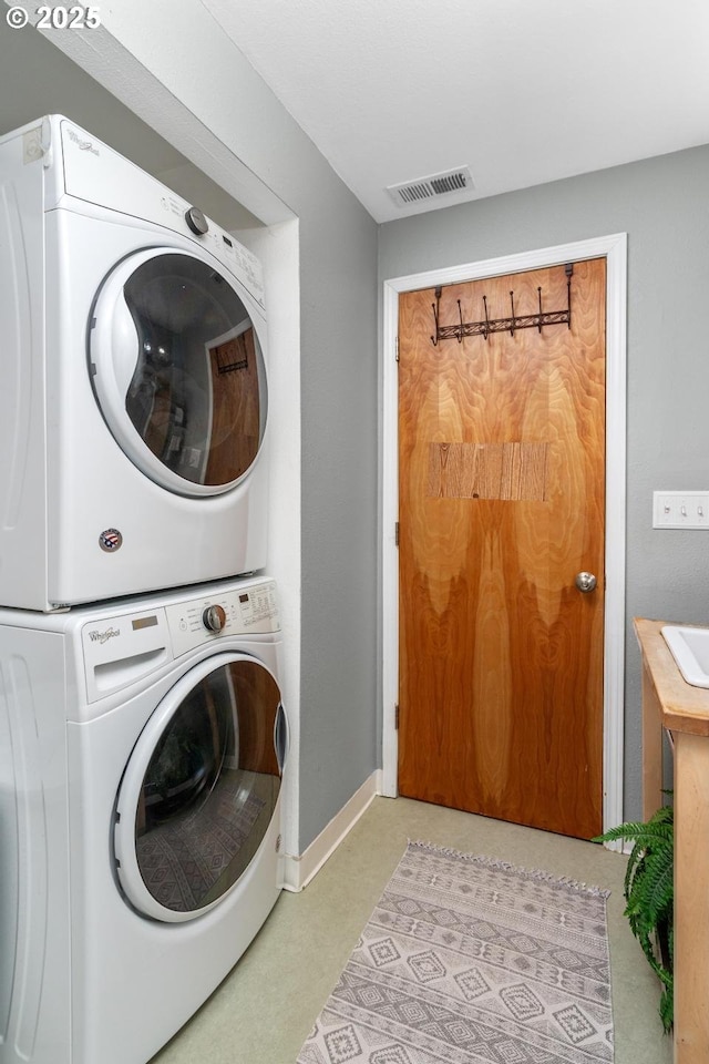 laundry room featuring stacked washer / drying machine, baseboards, and carpet flooring