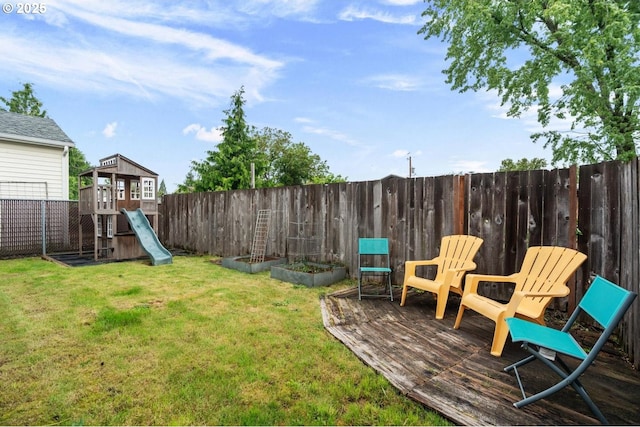 view of yard featuring a playground, a wooden deck, and a vegetable garden