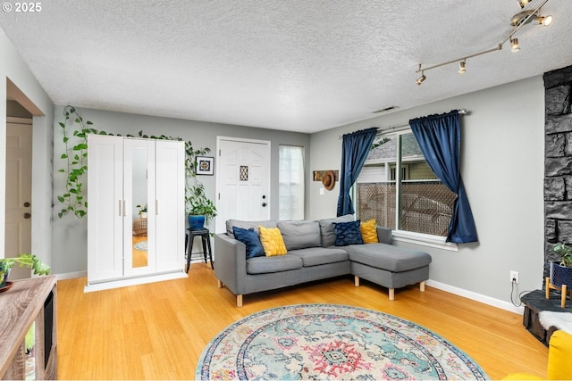 living area featuring wood finished floors, a textured ceiling, and baseboards