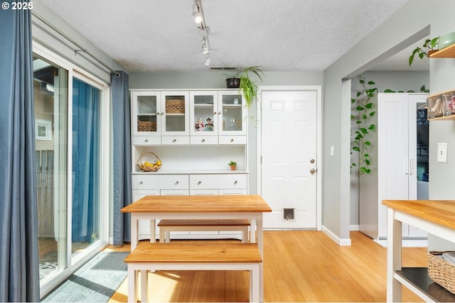 dining room with light wood-style flooring, a textured ceiling, and baseboards