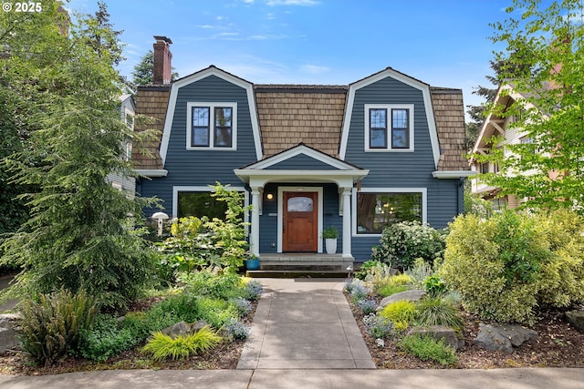 view of front of property with a gambrel roof, a chimney, and mansard roof