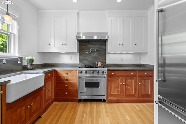 kitchen featuring a sink, decorative backsplash, white cabinets, high end appliances, and light wood-style floors
