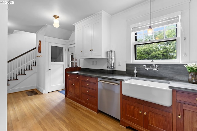 kitchen with a sink, decorative light fixtures, white cabinets, stainless steel dishwasher, and light wood-style floors