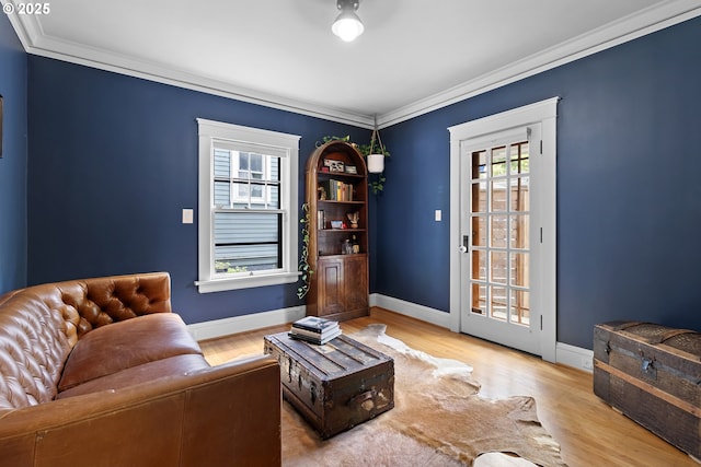 living area featuring baseboards, crown molding, and wood finished floors