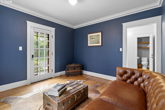 living room with wood finished floors, baseboards, and ornamental molding