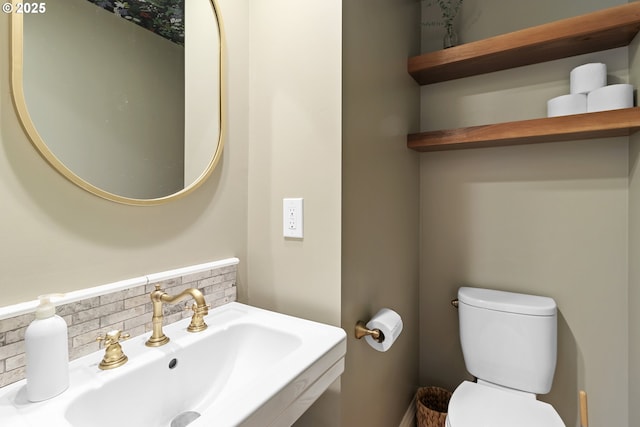 half bath featuring backsplash, toilet, and a sink