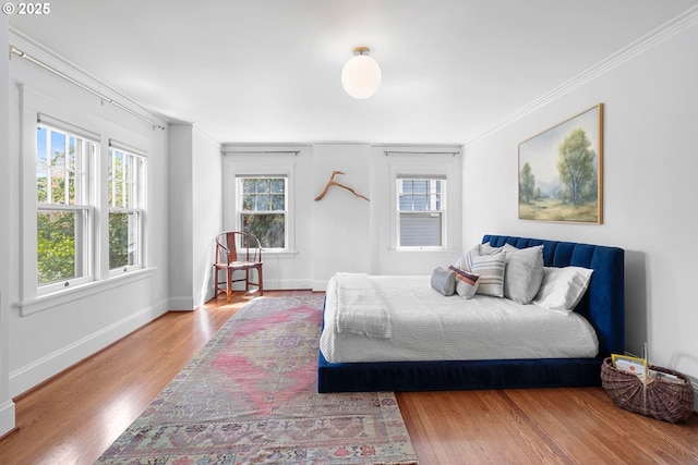 bedroom with baseboards, ornamental molding, and wood finished floors