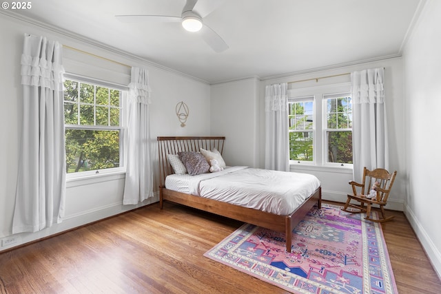bedroom featuring multiple windows, wood finished floors, and crown molding