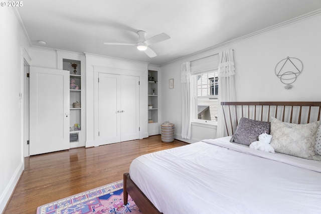 bedroom with a closet, ornamental molding, ceiling fan, visible vents, and wood finished floors