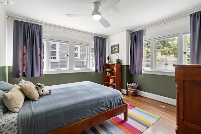 bedroom with baseboards, crown molding, ceiling fan, and wood finished floors