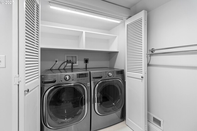 clothes washing area featuring laundry area, visible vents, and washing machine and clothes dryer