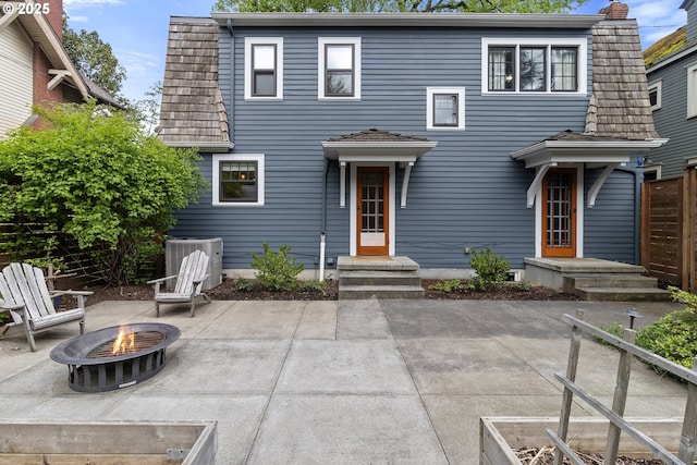 exterior space featuring central air condition unit, a patio area, a fire pit, and a chimney
