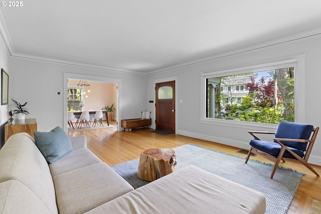 living area with baseboards, a chandelier, crown molding, and wood finished floors