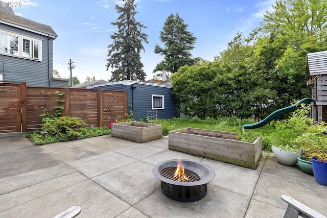 view of patio / terrace featuring a fire pit, a playground, a garden, and fence