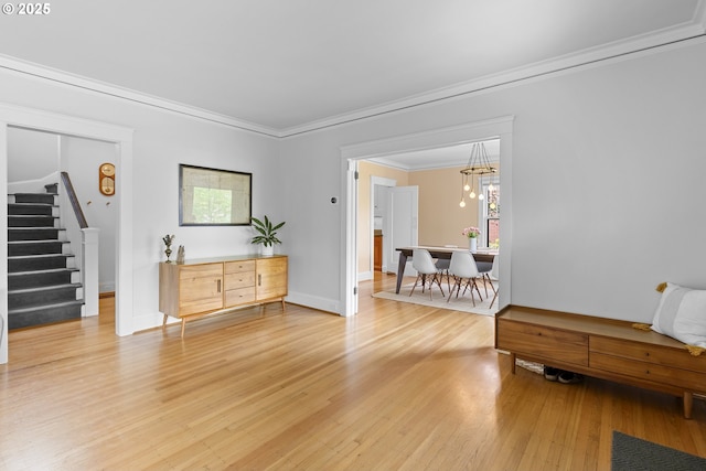 interior space featuring an inviting chandelier, stairway, baseboards, light wood-style floors, and ornamental molding