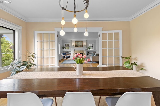 dining area featuring a fireplace, crown molding, and wood finished floors