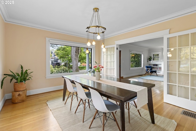 dining area featuring light wood-type flooring, crown molding, visible vents, and baseboards