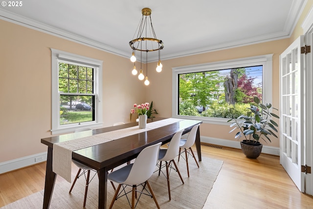 dining area with light wood finished floors, crown molding, a wealth of natural light, and visible vents