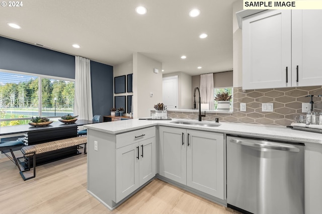 kitchen featuring sink, backsplash, stainless steel dishwasher, light stone countertops, and white cabinets