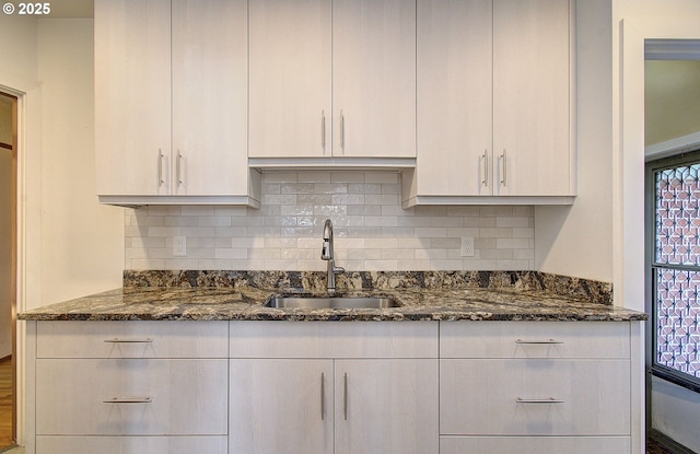 kitchen featuring sink, backsplash, and dark stone counters