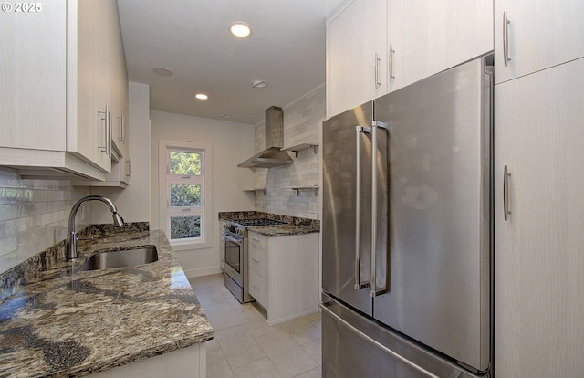 kitchen featuring wall chimney range hood, sink, dark stone countertops, backsplash, and high quality appliances