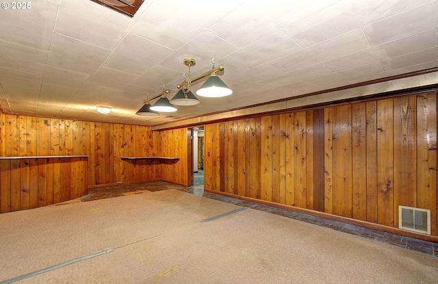 basement with indoor bar, wooden walls, and carpet