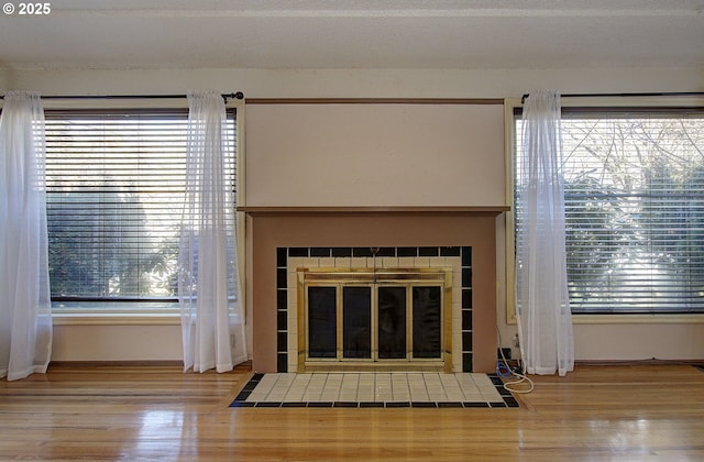 room details with a tiled fireplace, wood-type flooring, and a textured ceiling