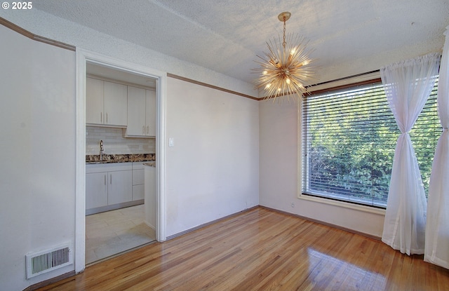 interior space with sink, a textured ceiling, a chandelier, and light hardwood / wood-style floors