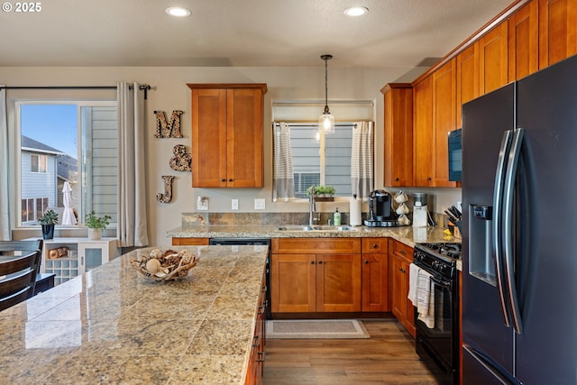 kitchen with black appliances, a kitchen island, dark wood-style flooring, and a sink