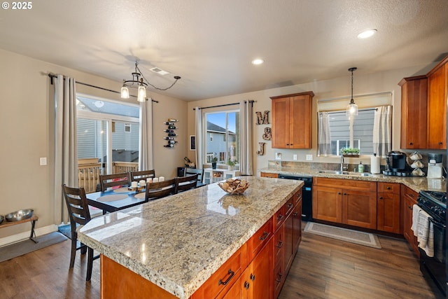 kitchen with black appliances, brown cabinets, a sink, and wood finished floors