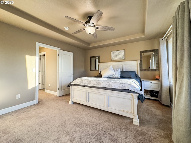 bedroom with a tray ceiling, dark carpet, and baseboards