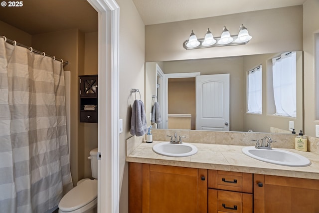 bathroom featuring toilet, double vanity, and a sink