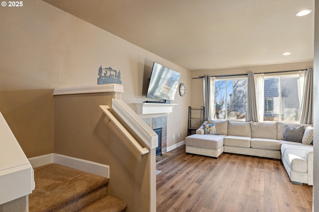 living area featuring recessed lighting, a fireplace, wood finished floors, baseboards, and stairs