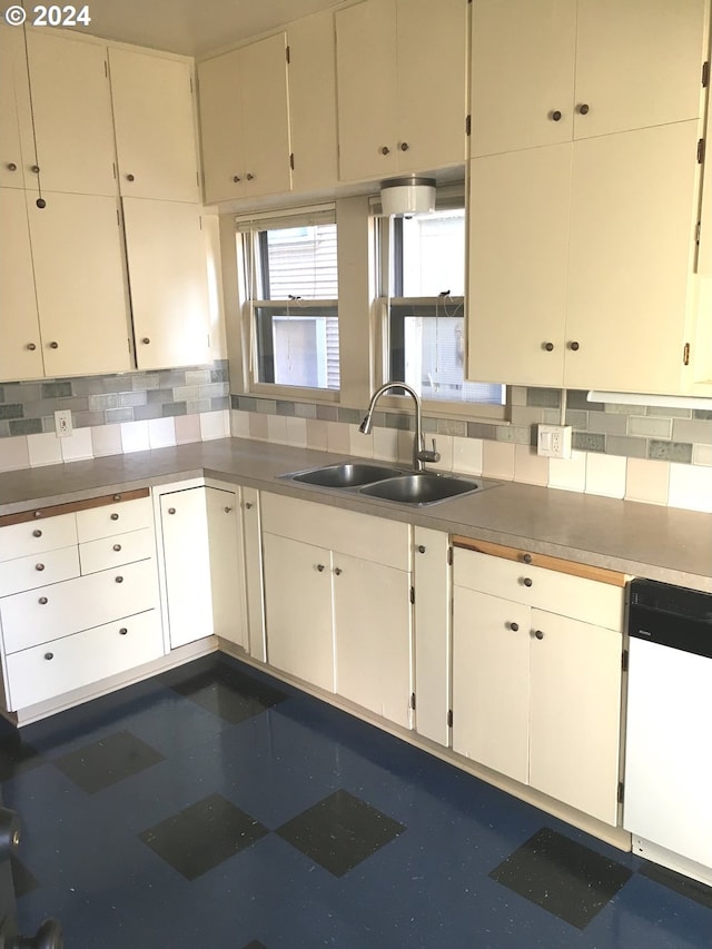 kitchen with tasteful backsplash, white cabinets, sink, and white dishwasher