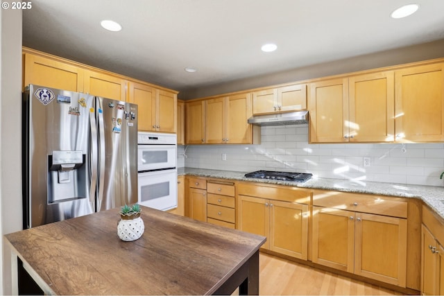 kitchen featuring backsplash, stainless steel appliances, and light stone countertops