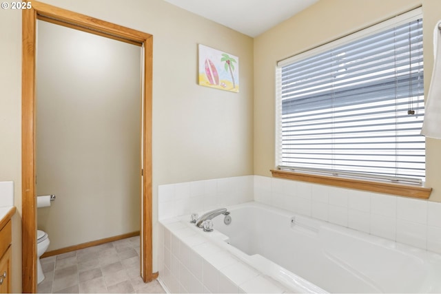 bathroom with vanity, a relaxing tiled tub, and toilet