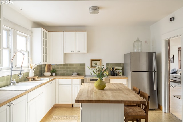 1818 N Killingsworth St, Portland, OR 97217 - kitchen with wood counters, freestanding refrigerator, a sink, glass insert cabinets, and a kitchen breakfast bar