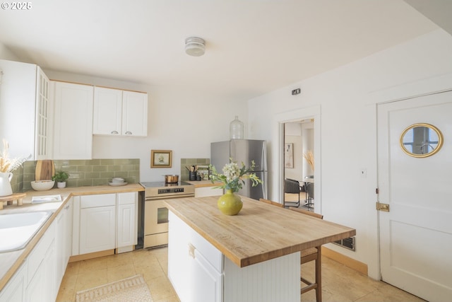 1818 N Killingsworth St, Portland, OR 97217 - kitchen featuring appliances with stainless steel finishes, wood counters, a kitchen bar, and white cabinetry
