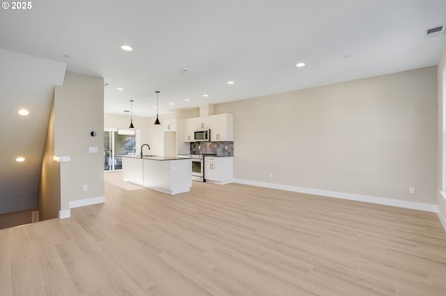 unfurnished living room with light wood-type flooring, a sink, and recessed lighting