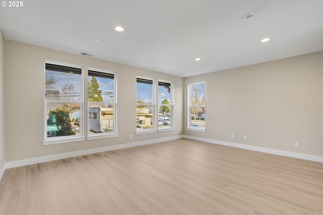 empty room with recessed lighting, baseboards, visible vents, and light wood finished floors