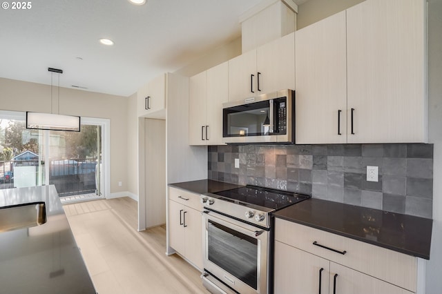 kitchen with light wood finished floors, decorative backsplash, dark countertops, decorative light fixtures, and stainless steel appliances