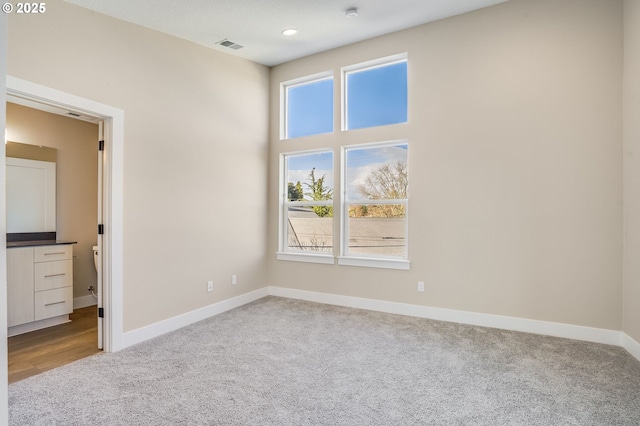 unfurnished bedroom featuring recessed lighting, carpet floors, a high ceiling, visible vents, and baseboards