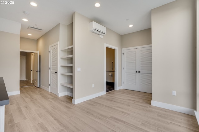 unfurnished bedroom featuring light wood-type flooring, visible vents, recessed lighting, and a wall mounted AC