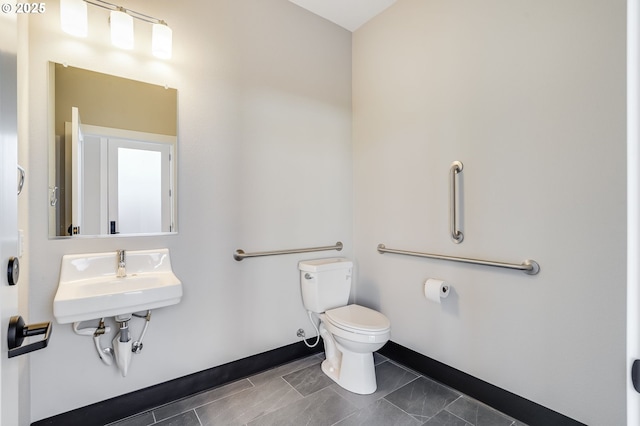 half bathroom with toilet, baseboards, and a sink