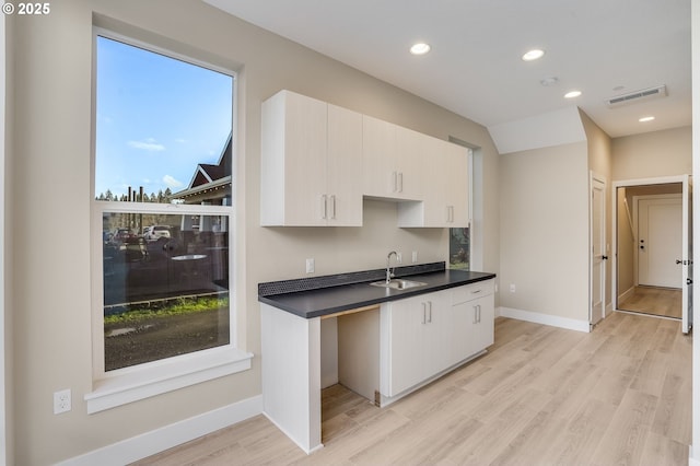 kitchen featuring dark countertops, recessed lighting, visible vents, light wood-style floors, and a sink